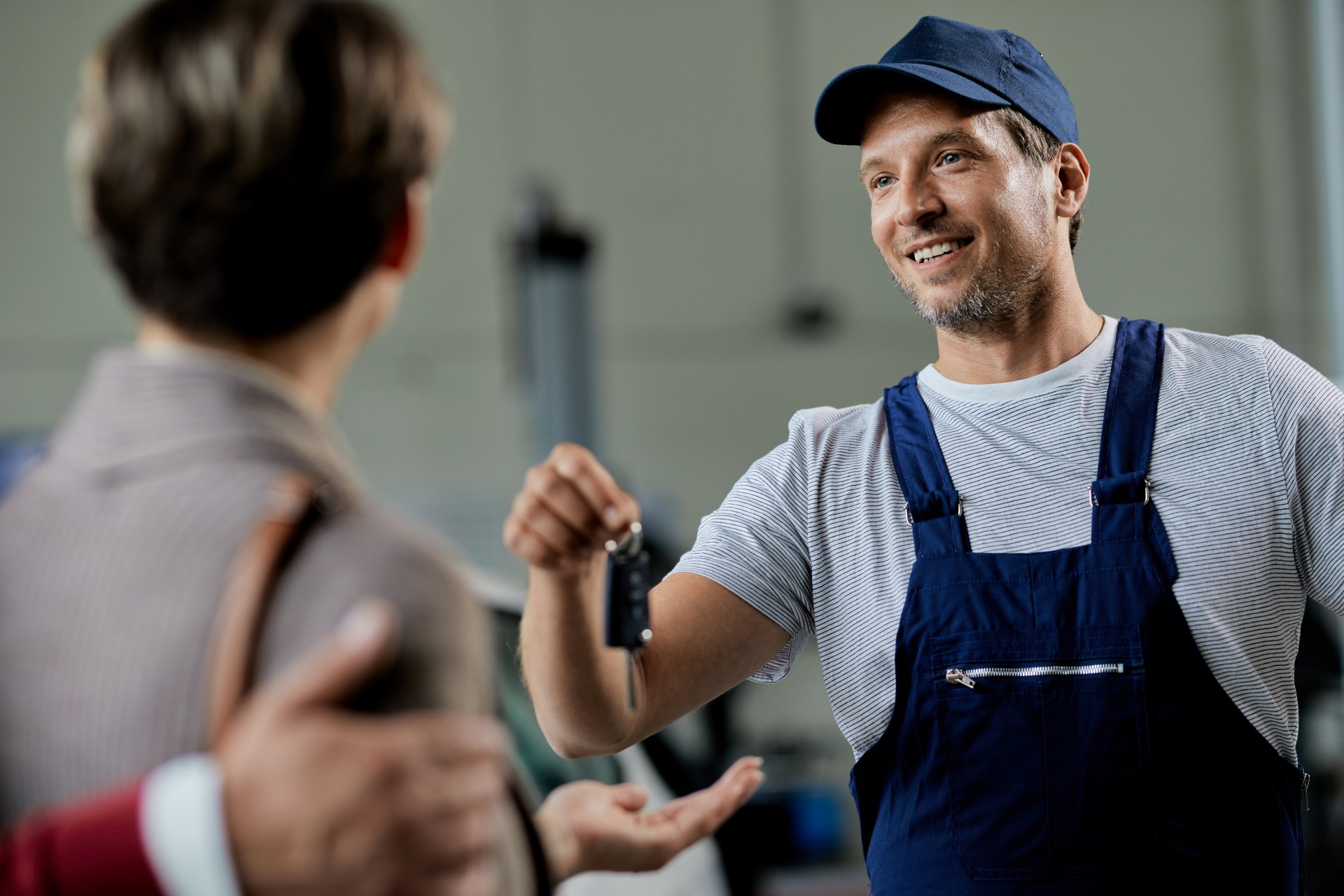 happy-auto-repairman-handing-cark-keys-his-customers-workshop